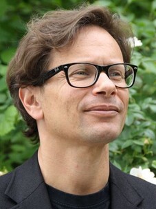 Fakher Assaad mit Brille und lockigem Haar, nachdenklich im Freien aufgenommen.